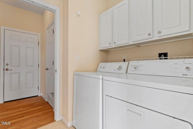 washroom featuring cabinet space, separate washer and dryer, baseboards, and light wood-style floors