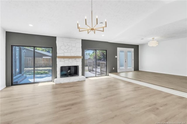 unfurnished living room featuring a wealth of natural light, a fireplace, recessed lighting, and a notable chandelier