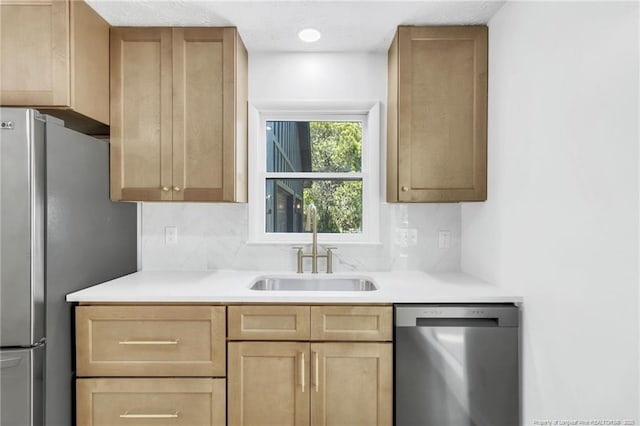 kitchen with light countertops, appliances with stainless steel finishes, a sink, and light brown cabinets
