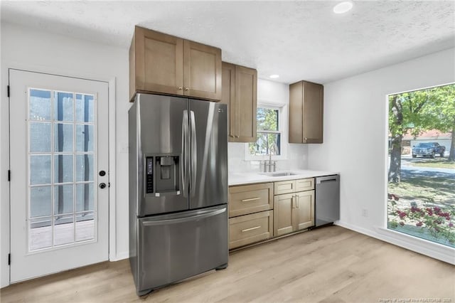kitchen featuring a sink, appliances with stainless steel finishes, light wood-style floors, and light countertops