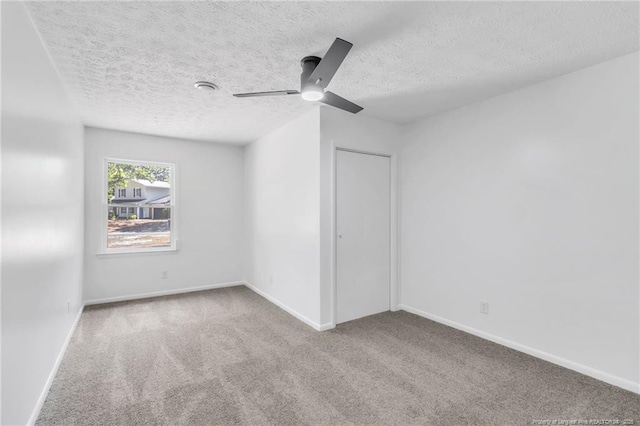 spare room featuring carpet floors, a textured ceiling, ceiling fan, and baseboards