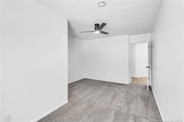 carpeted spare room featuring baseboards, a ceiling fan, and a textured ceiling