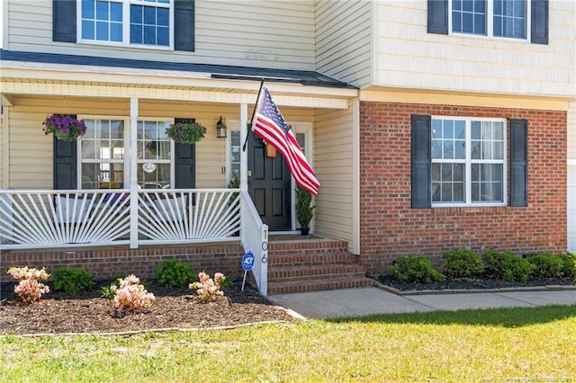 doorway to property featuring brick siding and a porch