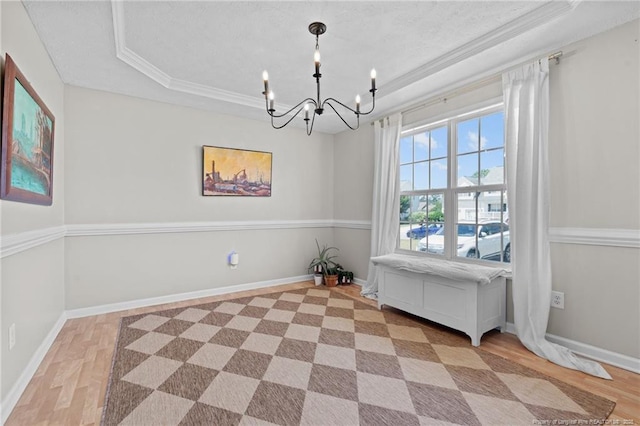 dining area with ornamental molding, a tray ceiling, light wood-type flooring, and a notable chandelier