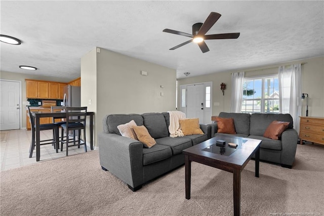 living area with light colored carpet, a ceiling fan, and a textured ceiling