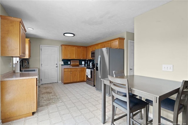 kitchen with light floors, recessed lighting, light countertops, a sink, and appliances with stainless steel finishes