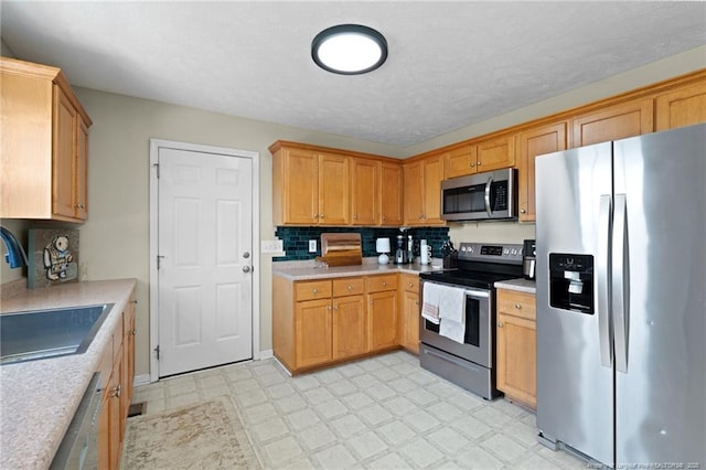 kitchen featuring a sink, light countertops, light floors, stainless steel appliances, and tasteful backsplash
