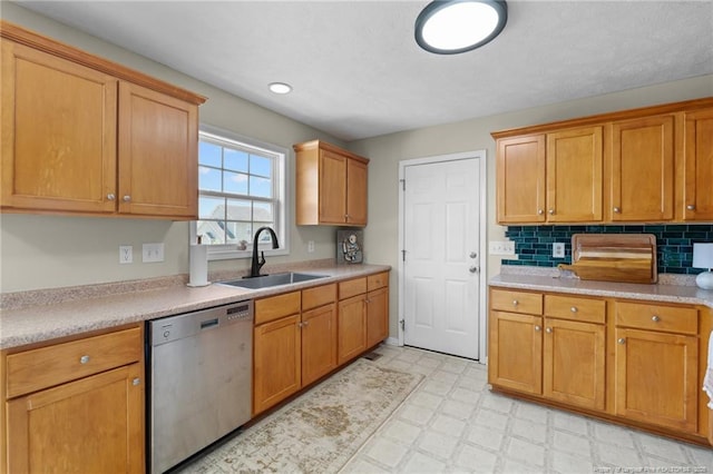 kitchen featuring tasteful backsplash, stainless steel dishwasher, a sink, light countertops, and light floors