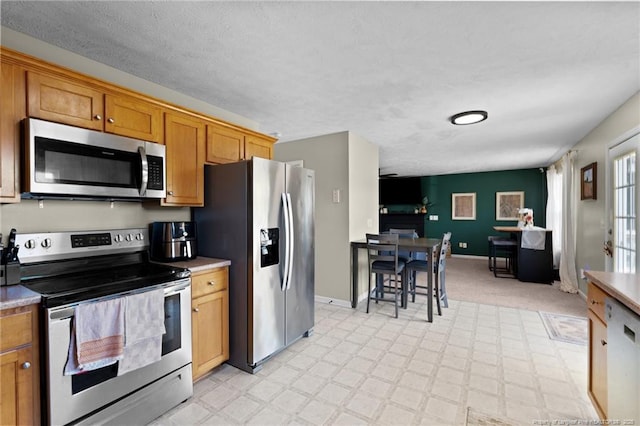 kitchen with brown cabinets, light countertops, stainless steel appliances, baseboards, and light floors