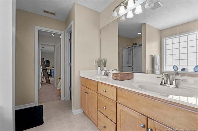 full bath with double vanity, visible vents, a sink, and a stall shower