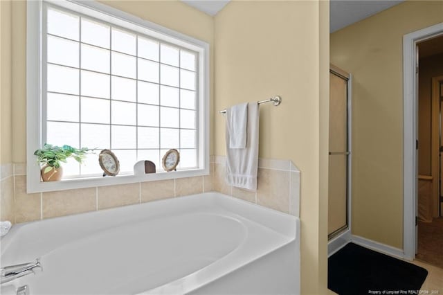 bathroom featuring a shower stall, a wealth of natural light, and a garden tub
