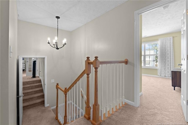 stairway featuring baseboards, a textured ceiling, carpet, and a chandelier