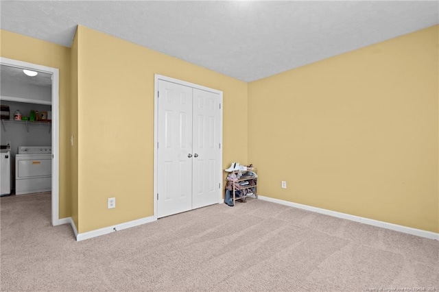 unfurnished bedroom featuring carpet floors, baseboards, a closet, and washer and clothes dryer