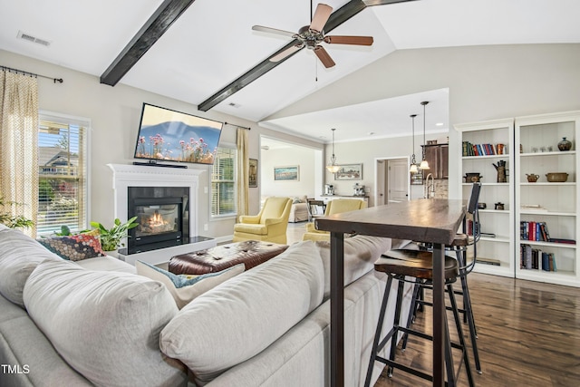 living area featuring a glass covered fireplace, a ceiling fan, lofted ceiling, dark wood-type flooring, and visible vents