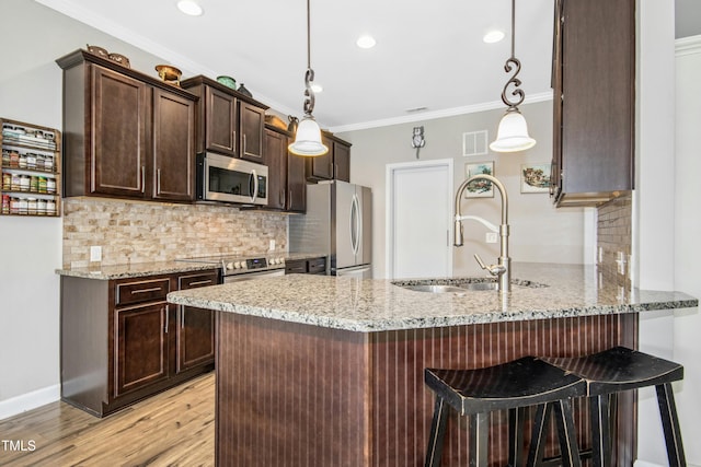 kitchen with visible vents, dark brown cabinetry, light stone counters, a sink, and stainless steel appliances