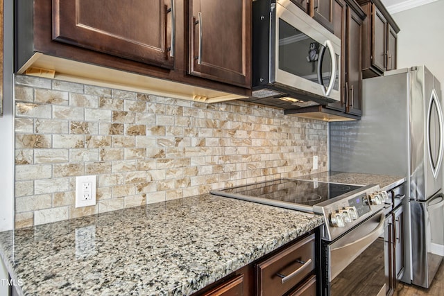 kitchen featuring crown molding, dark brown cabinets, light stone countertops, appliances with stainless steel finishes, and wood finished floors