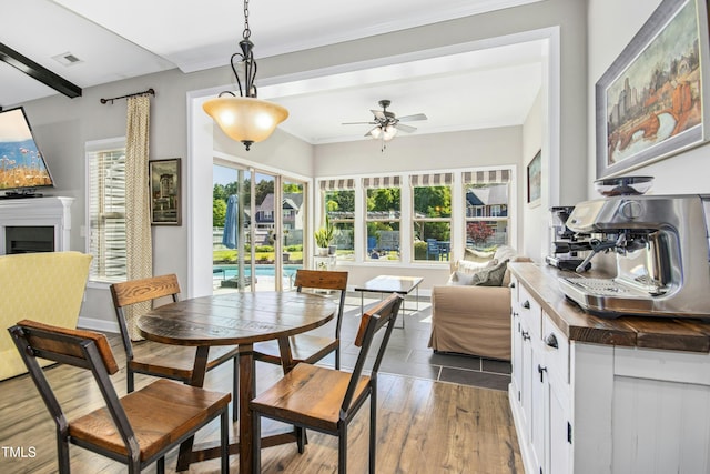 dining area featuring a ceiling fan, visible vents, wood finished floors, and a fireplace