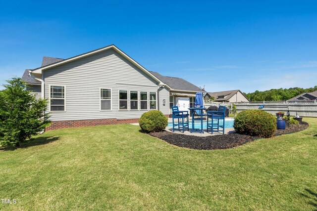 rear view of house featuring a fenced backyard, a fenced in pool, a lawn, and a patio area