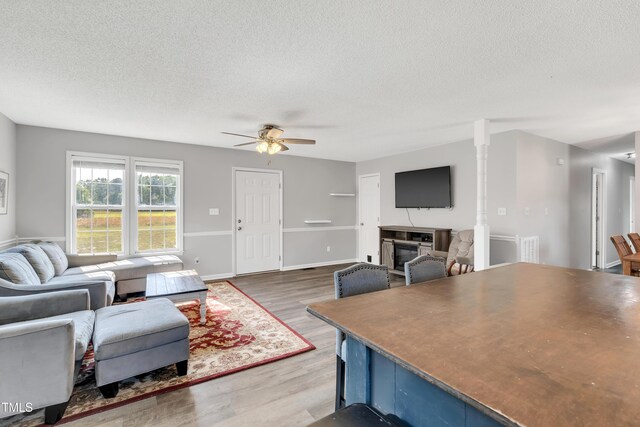 640 Short Journey Rd, Smithfield, NC 27577 - living room featuring visible vents, a glass covered fireplace, wood finished floors, a textured ceiling, and a ceiling fan