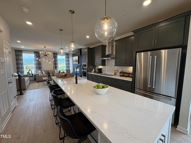 kitchen featuring high end fridge, open floor plan, black electric cooktop, wall chimney range hood, and recessed lighting