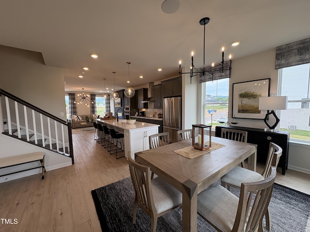 dining room with stairs, light wood-type flooring, baseboards, recessed lighting, and a notable chandelier