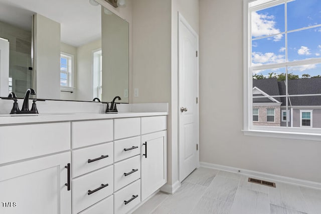 full bath with double vanity, visible vents, baseboards, and a sink