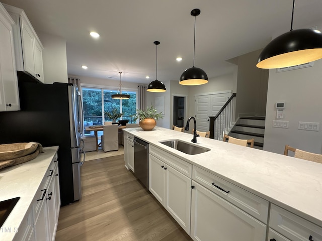 5906 Dunzo Dr, Raleigh, NC 27617 - kitchen with appliances with stainless steel finishes, recessed lighting, white cabinets, wood finished floors, and hanging light fixtures