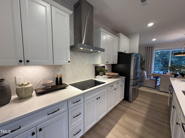 5906 Dunzo Dr, Raleigh, NC 27617 - kitchen with wall chimney exhaust hood, black electric stovetop, freestanding refrigerator, backsplash, and white cabinets