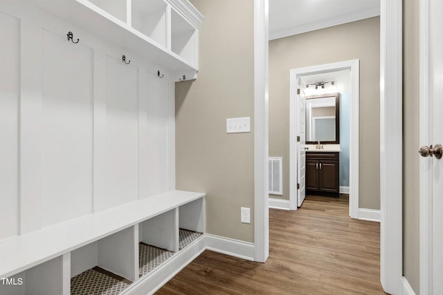 mudroom with visible vents, a sink, baseboards, and wood finished floors
