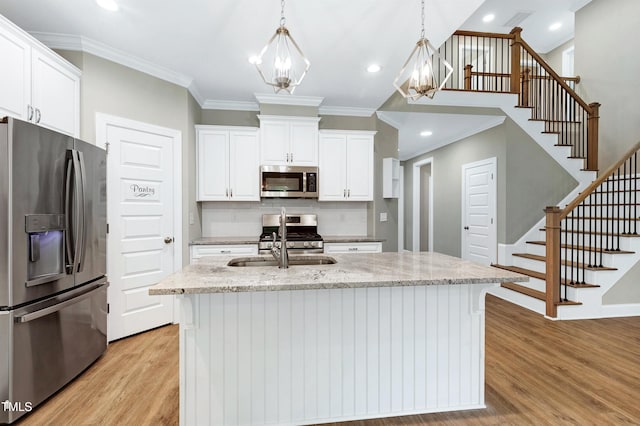 kitchen with light wood-type flooring, ornamental molding, white cabinets, and stainless steel appliances