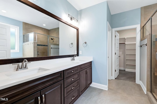 full bath with double vanity, a sink, a spacious closet, and a shower stall