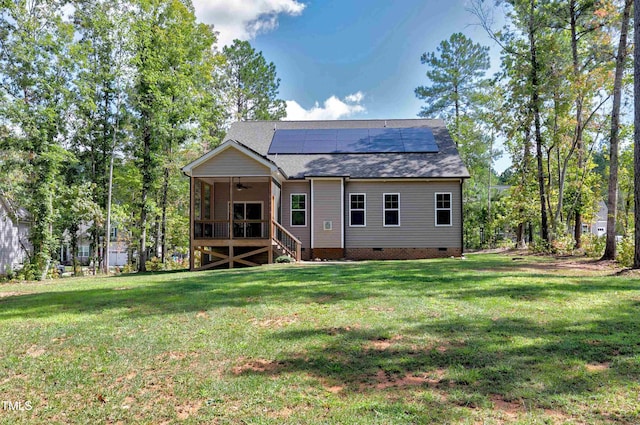 rear view of property with ceiling fan, a shingled roof, crawl space, a yard, and solar panels