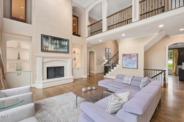 3601 Nightfall Ct, Raleigh, NC 27607 - living area featuring arched walkways, built in features, a towering ceiling, wood finished floors, and a fireplace