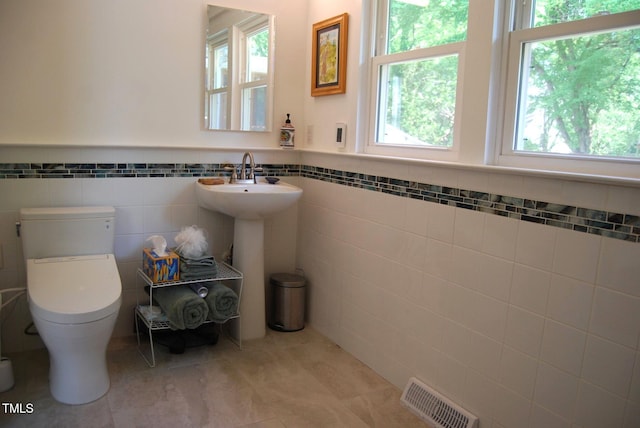 1013 Green St, Durham, NC 27701 - half bathroom with visible vents, tile patterned flooring, wainscoting, toilet, and tile walls