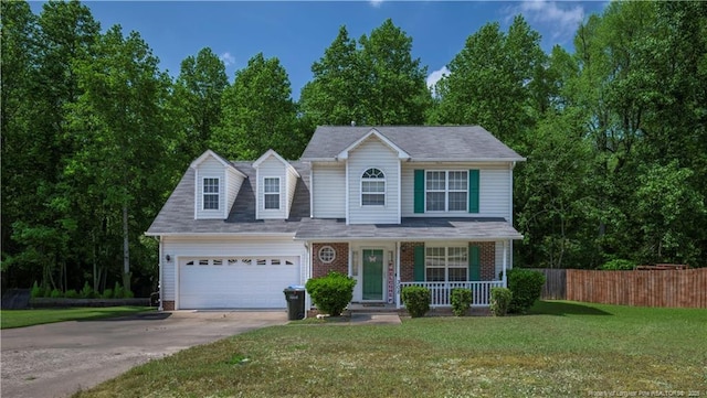 traditional-style home featuring fence, an attached garage, a porch, a front yard, and concrete driveway