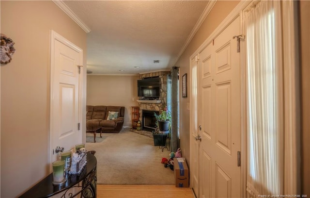 hall with ornamental molding, light wood-type flooring, and a textured ceiling