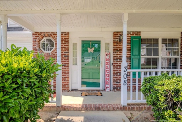 property entrance with a porch and brick siding