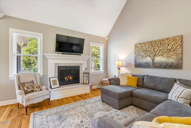 2062 Montgomery Dr, Franklinton, NC 27525 - living room featuring wood finished floors, vaulted ceiling, plenty of natural light, baseboards, and a glass covered fireplace