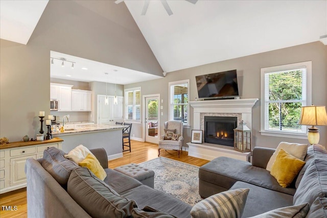 2062 Montgomery Dr, Franklinton, NC 27525 - living area featuring light wood finished floors, a glass covered fireplace, a ceiling fan, high vaulted ceiling, and baseboards