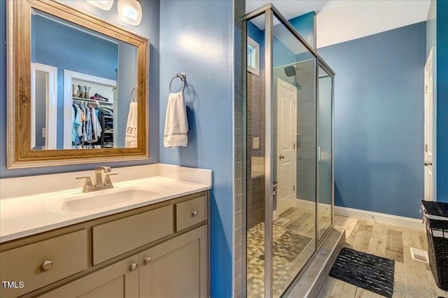 2062 Montgomery Dr, Franklinton, NC 27525 - bathroom featuring a stall shower, vanity, a walk in closet, and wood finished floors