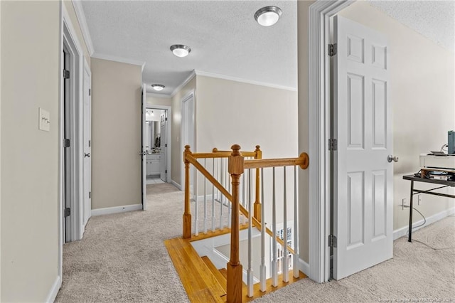 corridor with carpet flooring, a textured ceiling, an upstairs landing, and ornamental molding