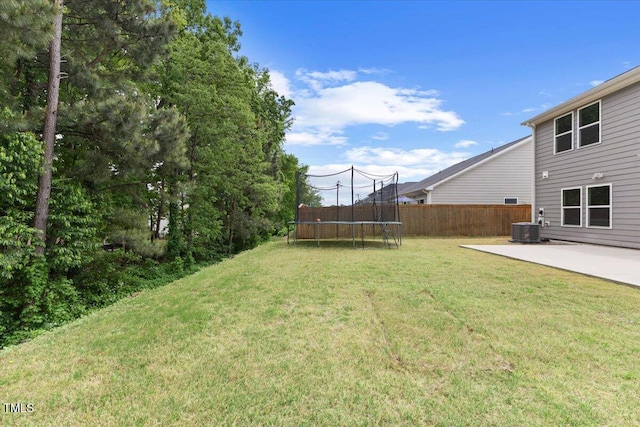 view of yard with a patio, a trampoline, central AC, and fence