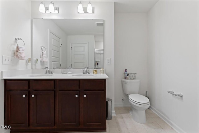 bathroom with a sink, tile patterned floors, toilet, and double vanity