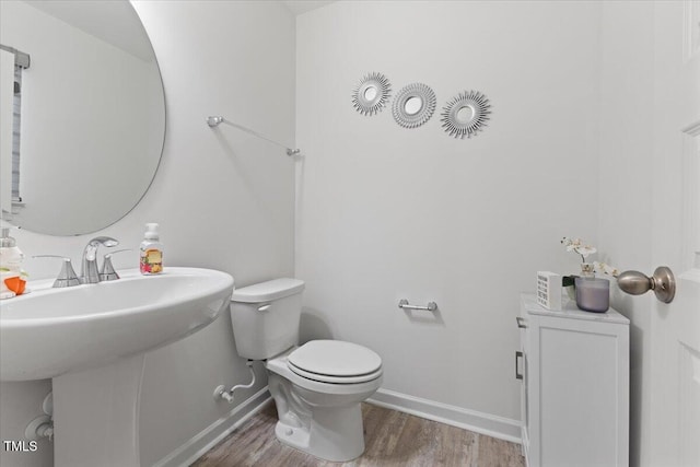 half bathroom featuring baseboards, toilet, and wood finished floors