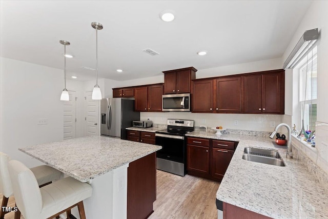 kitchen featuring a kitchen island, a kitchen breakfast bar, tasteful backsplash, a sink, and stainless steel appliances