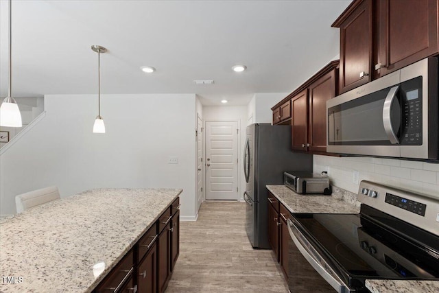 kitchen featuring light stone countertops, light wood-style flooring, stainless steel appliances, backsplash, and visible vents