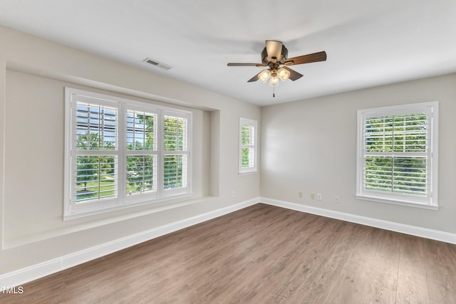 unfurnished room featuring baseboards, a ceiling fan, wood finished floors, and visible vents