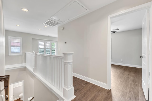 corridor featuring visible vents, an upstairs landing, wood finished floors, and attic access