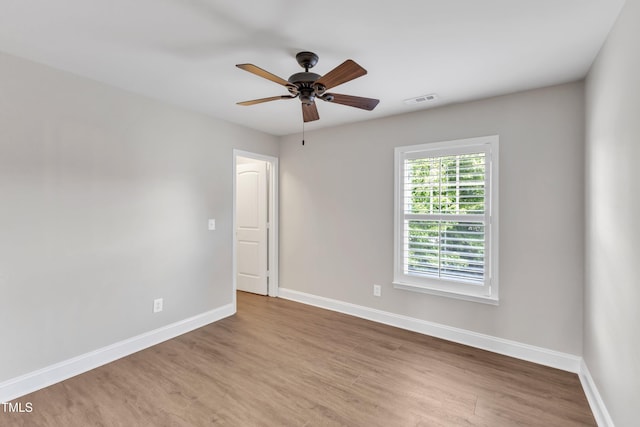 unfurnished room featuring a ceiling fan, baseboards, visible vents, and wood finished floors