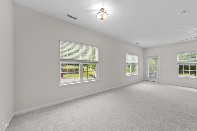 empty room featuring baseboards, a healthy amount of sunlight, visible vents, and carpet floors